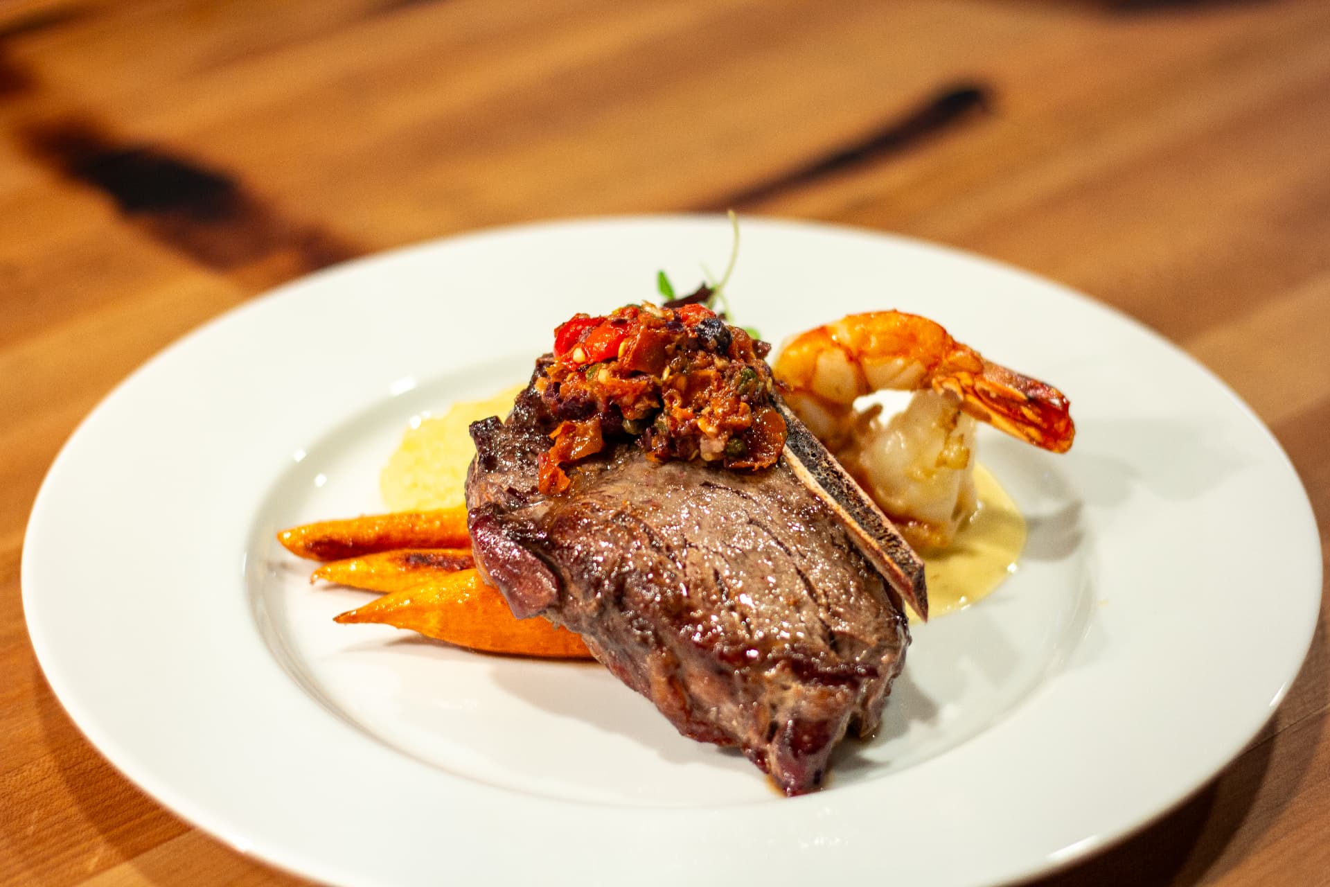 Bone-in steak with prawn, carrots and polenta